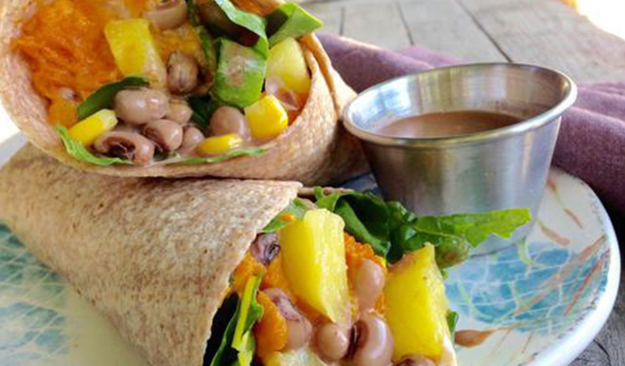 A burrito with beans, cheese and mango on top.